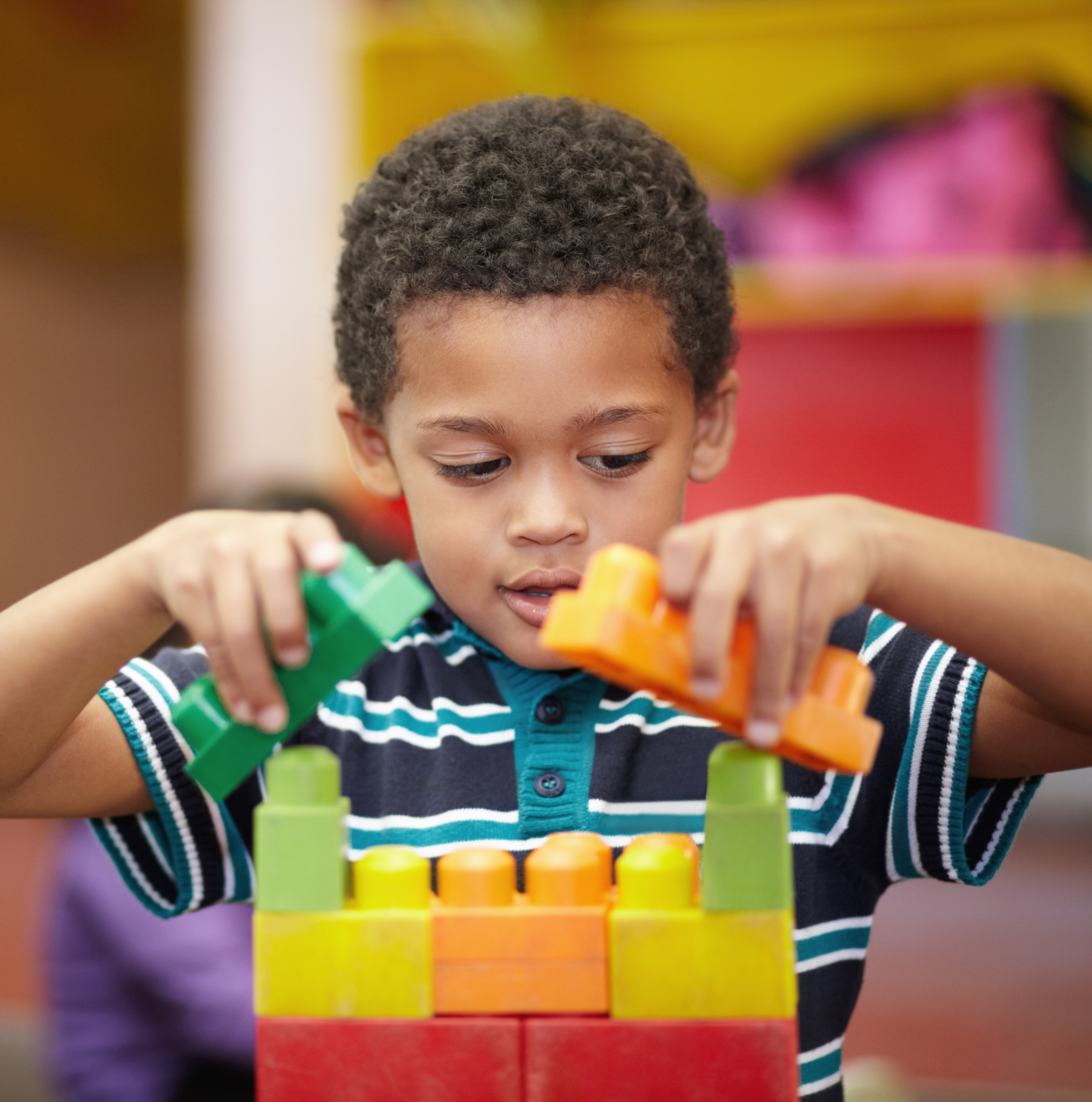 An interested pre-school child building something with plastic blocks